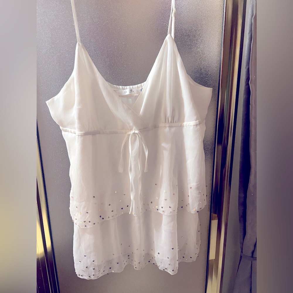 Flowing white layered top with silver sequin accents.